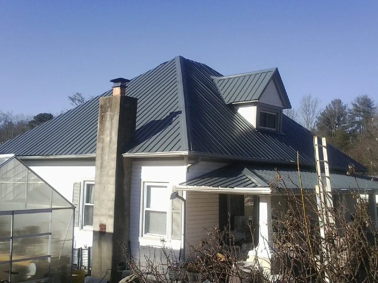 Dark blue standing seam metal roof on a white farmhouse with dormer — Slate & Tile Roof Repair by Roofing Brothers in Cadiz