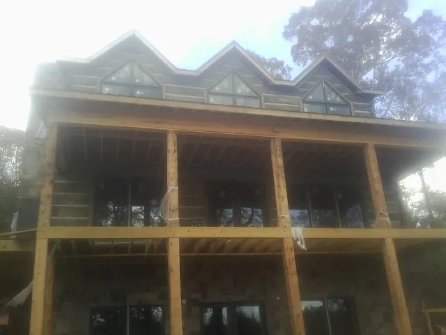 Dormers and porch framing on a large log home under construction — Roof Coating work by our crew in Cadiz