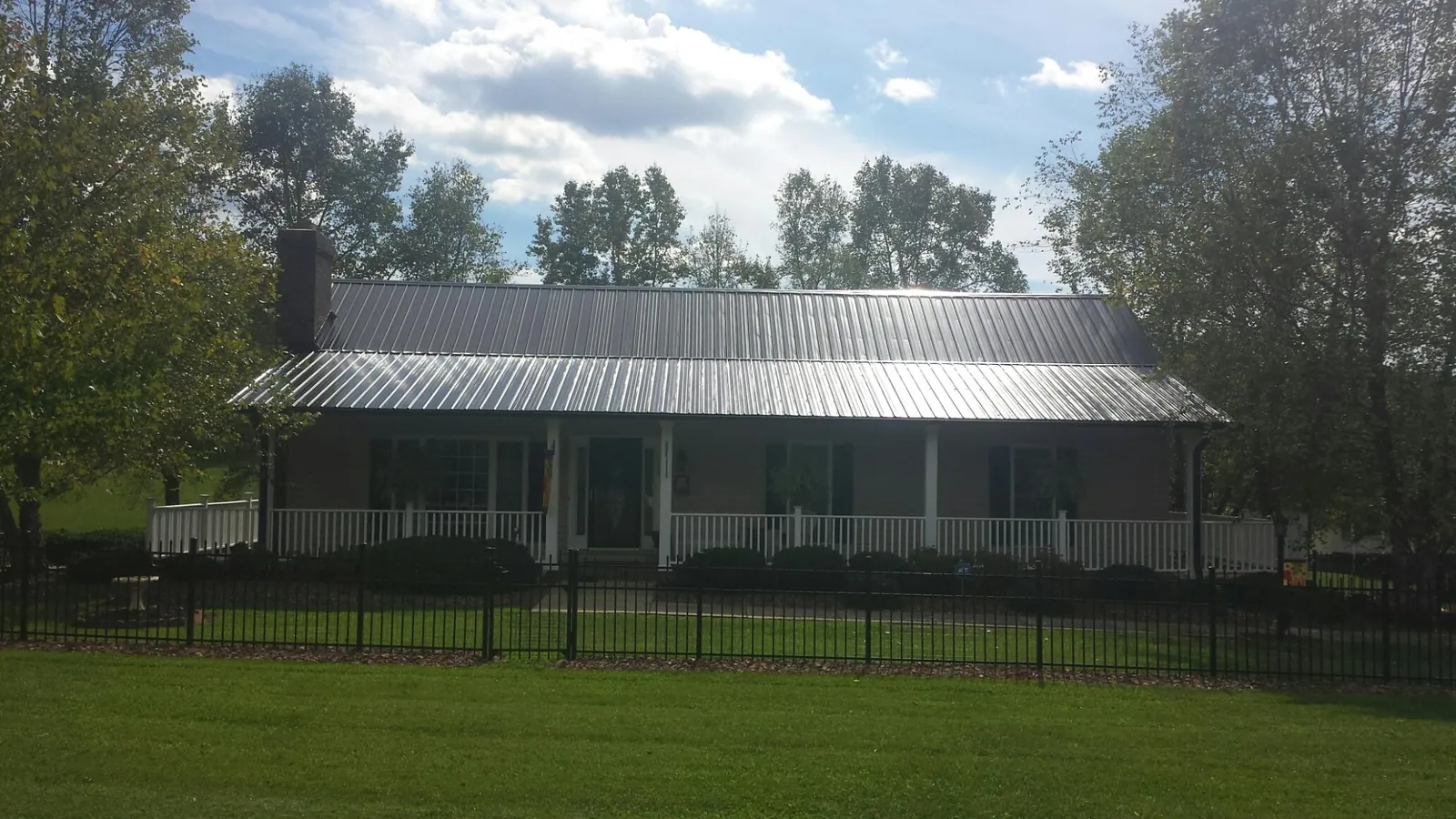 Gray metal roof on a brick ranch with a full width front porch — Gutter Guard Installation work by our crew in Cadiz